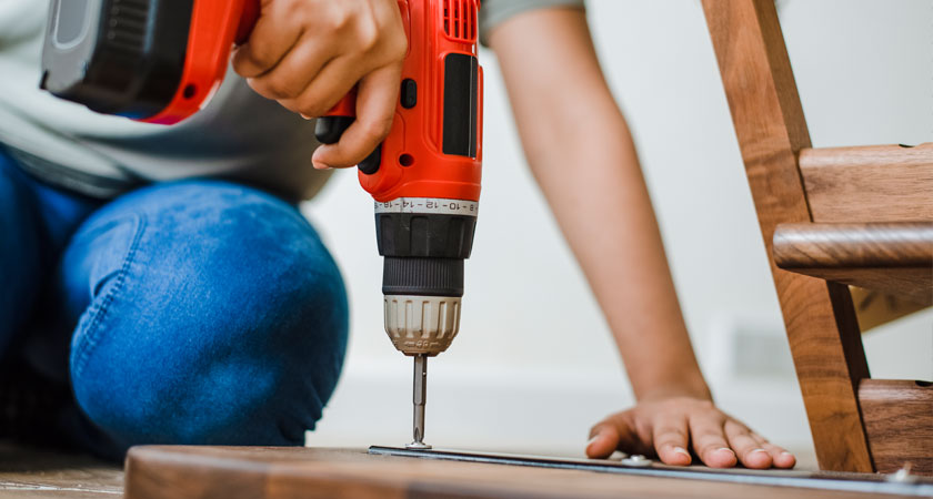 A person using an electric drill to install the floor.
