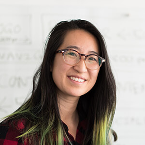 A woman with long hair and glasses smiling for the camera.