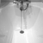 A white bathtub with a shower head and faucet.