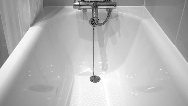 A white bathtub with a shower head and faucet.