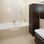 A bathroom with a tub, sink and mirror.