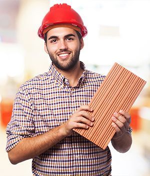 A man holding a piece of wood wearing a red hat.