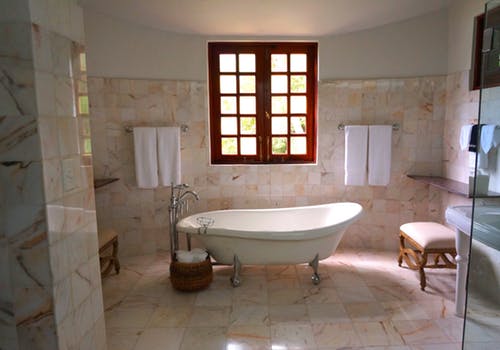 A bathroom with a tub, toilet and window.