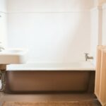 A bathroom with a tub, sink and mirror.