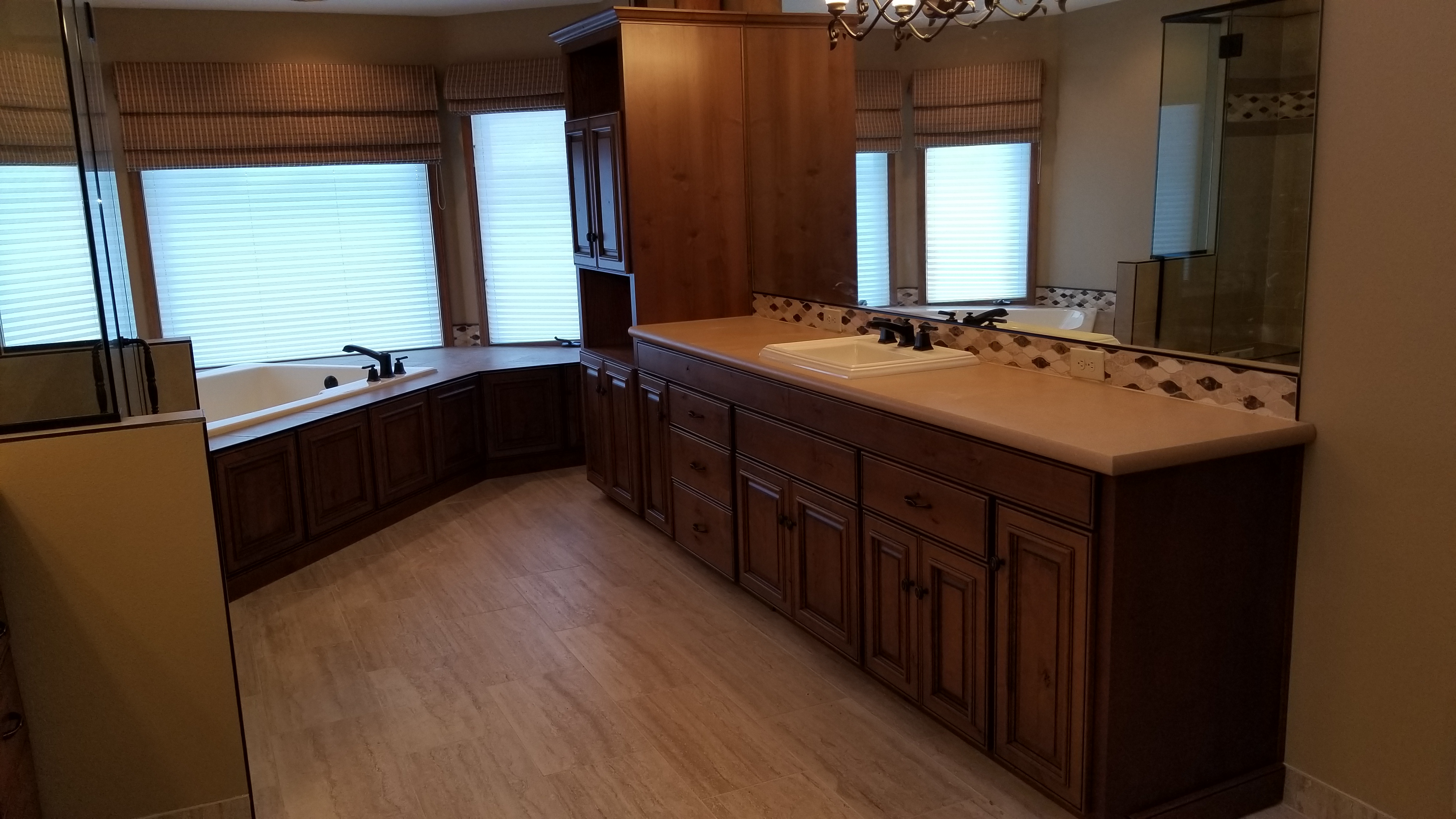 A large bathroom with wooden cabinets and floors.