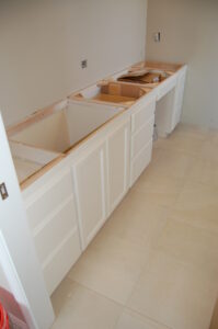 A kitchen with white cabinets and drawers being built.